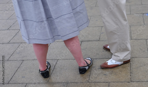 Couple wearing fancy shoes standing on paving stones, legs only