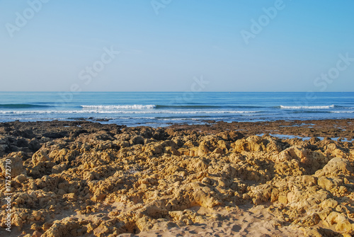Wild summer ocean beach, Portugal. Clear sky, Rocks on sand