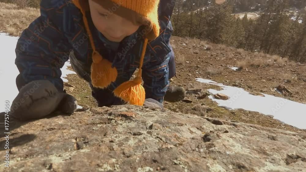 A steadicam follow shot of a little boy in snowsuit and a toque climbing a snowy hill in the forest A steadicam follow shot of a little boy in snowsuit and a toque climbing a snowy hill in the forest