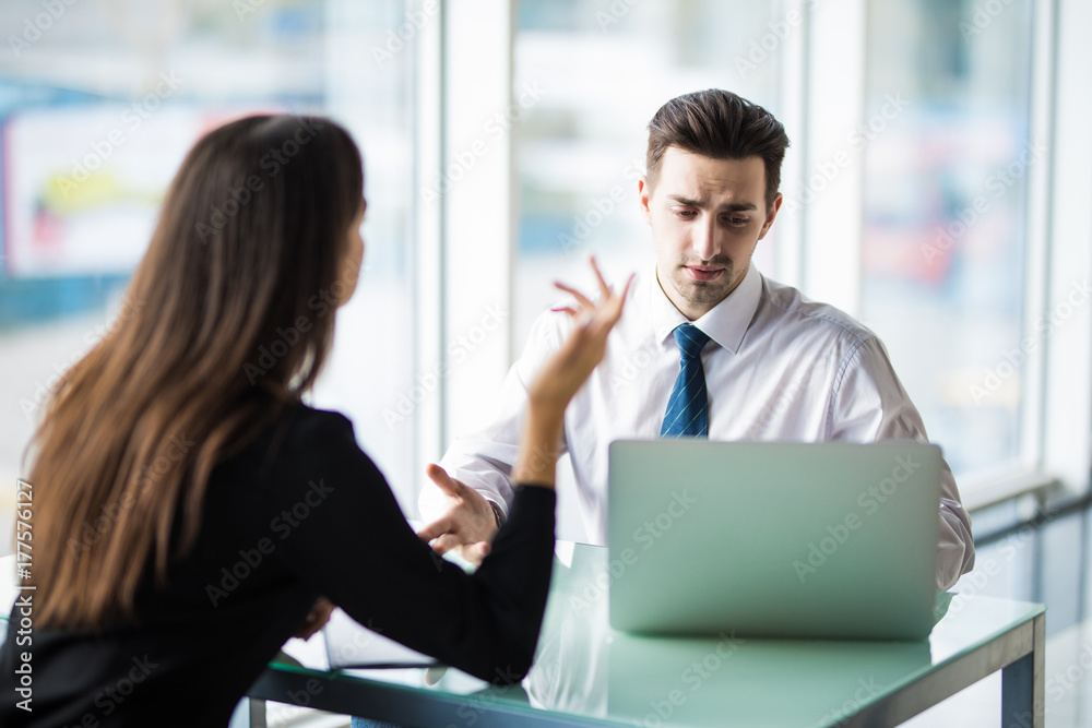 Businesswoman and businessman talking at work while working on new project on laptop Businesswoman and businessman talking at work while working on new project on laptop