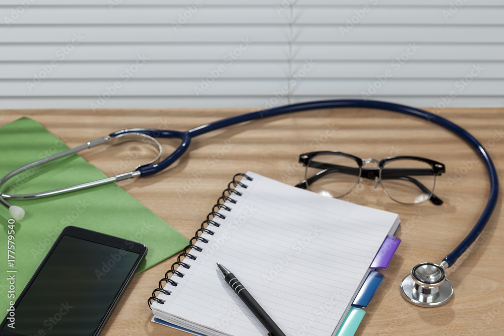 Stethoscope and a notepad laying on a doctors desk Stethoscope and a notepad laying on a doctors desk
