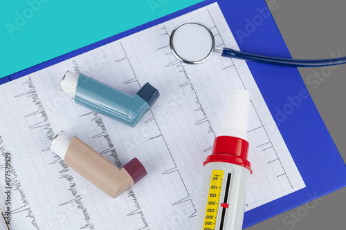 Asthma inhalers and a peak flow meter on a medical clipboard photo