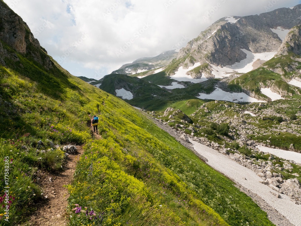 A tourist walks along a trail through a pass high in the mountains
