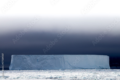 A tabular iceberg with a dark sky backdrop