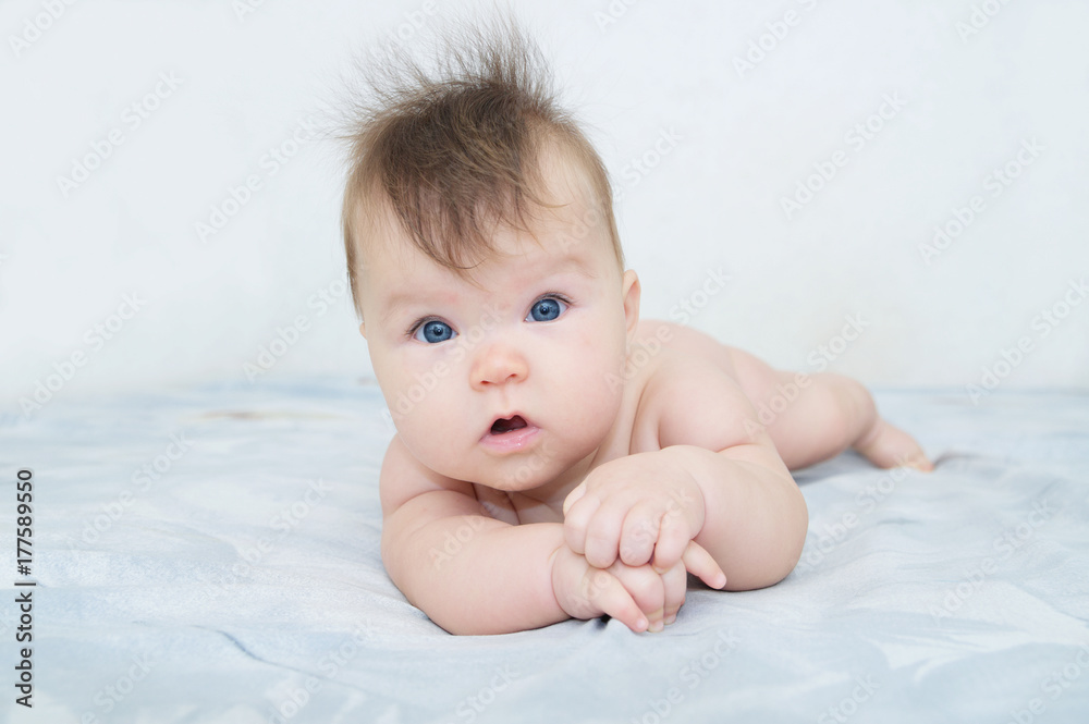 Newborn baby portrait cute and adorable in her three month, infant child with blue eyes lying on bed looking at camera Newborn baby portrait cute and adorable in her three month, infant child with blue eyes lying on bed looking at camera