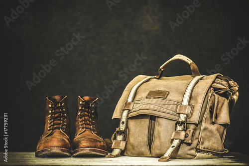 Men's boots and brown bag on wooden table 