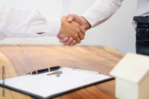 Estate agent shaking hands with customer after contract signature as successful agreement in real estate agency office. Concept of housing purchase and insurance