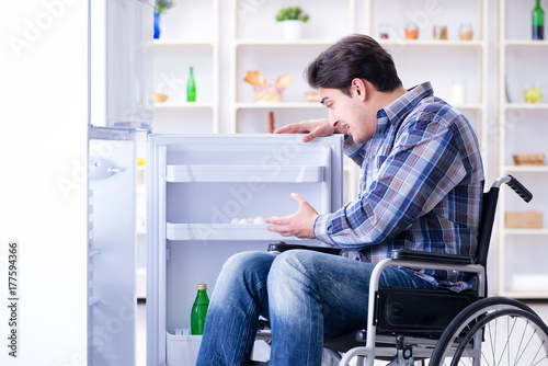 Young disabled injured man opening the fridge door 