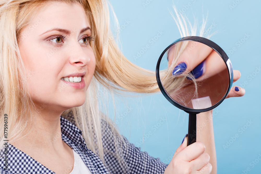 Woman looking at hair through magnifying glass Woman looking at hair through magnifying glass