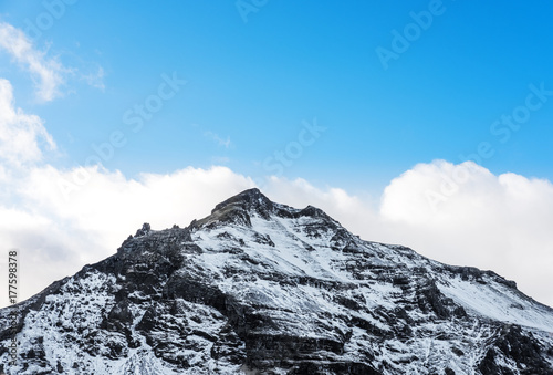 Mountain peak with snow and blue sky with white clouds in winter, winter landscape in Iceland
