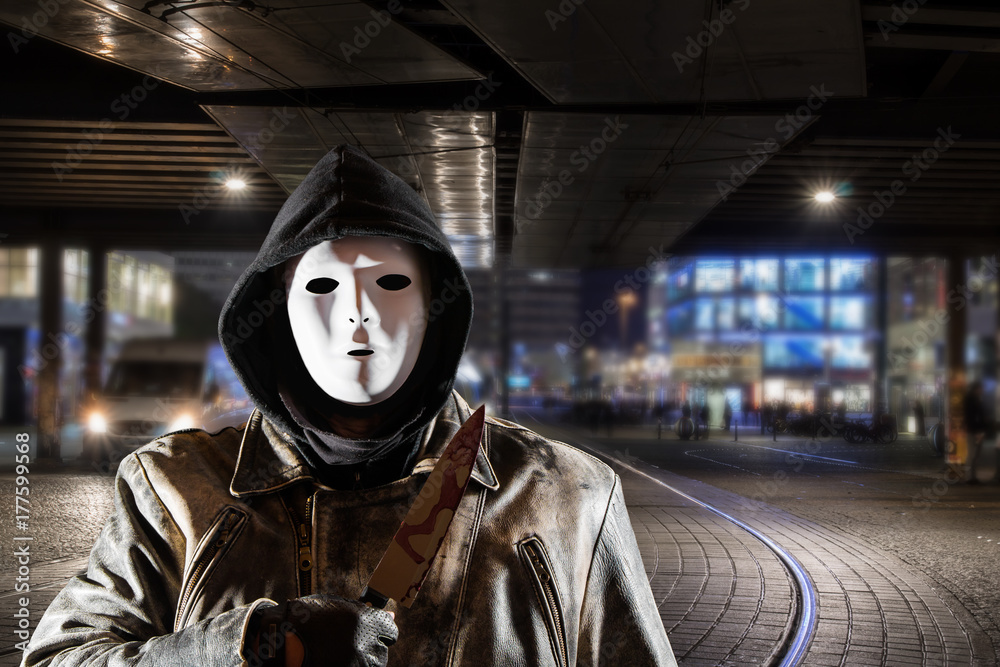 a masked man stands with a bloody knife at night in a city a masked man stands with a bloody knife at night in a city