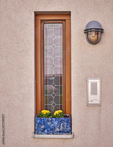 narrow window with yellow flowers, ringbell and light photo