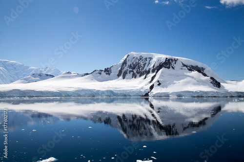 A mountain in Antarctica reflects in the water.
