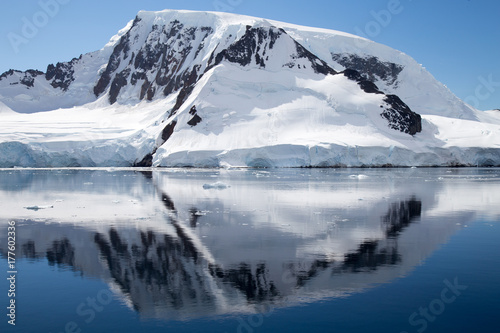 A mountain in Antarctica reflects in the water.