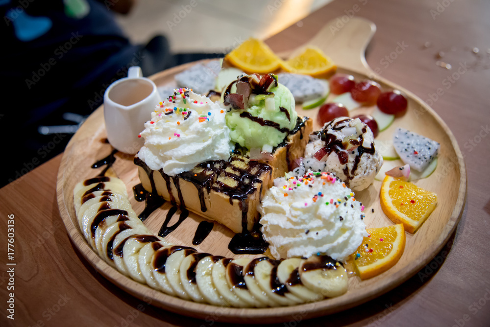 Fruit honey toast. dessert on the wood plate that is Toast and ice-cream top with strawberry and syrup dip Fruit honey toast. dessert on the wood plate that is Toast and ice-cream top with strawberry and syrup dip