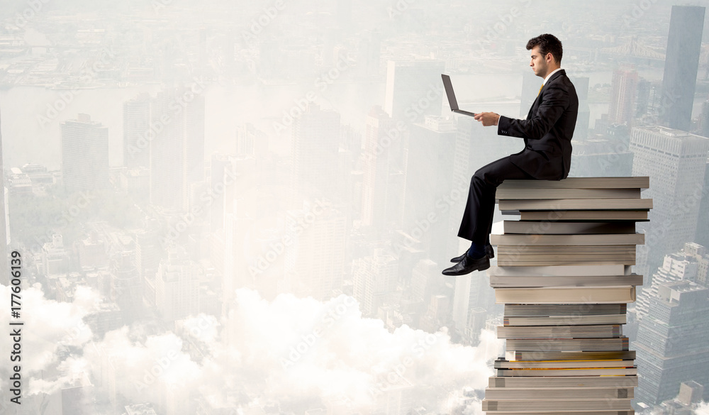 Student in city sitting on stack of books Student in city sitting on stack of books