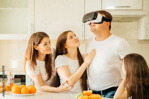 Father, wife and daughters in virtual reality glasses having fun at home photo