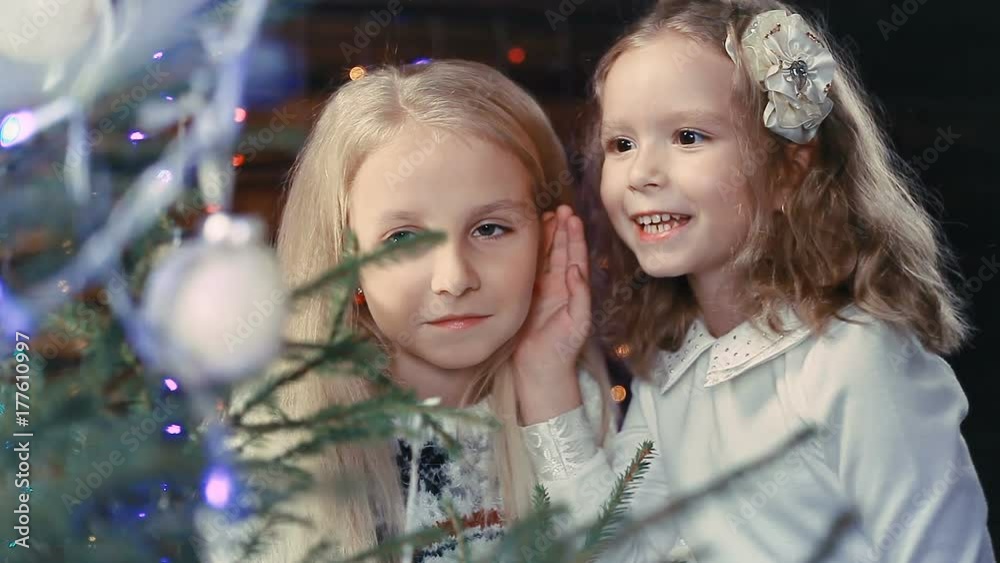 Two little girls decorate a Christmas tree Two little girls decorate a Christmas tree