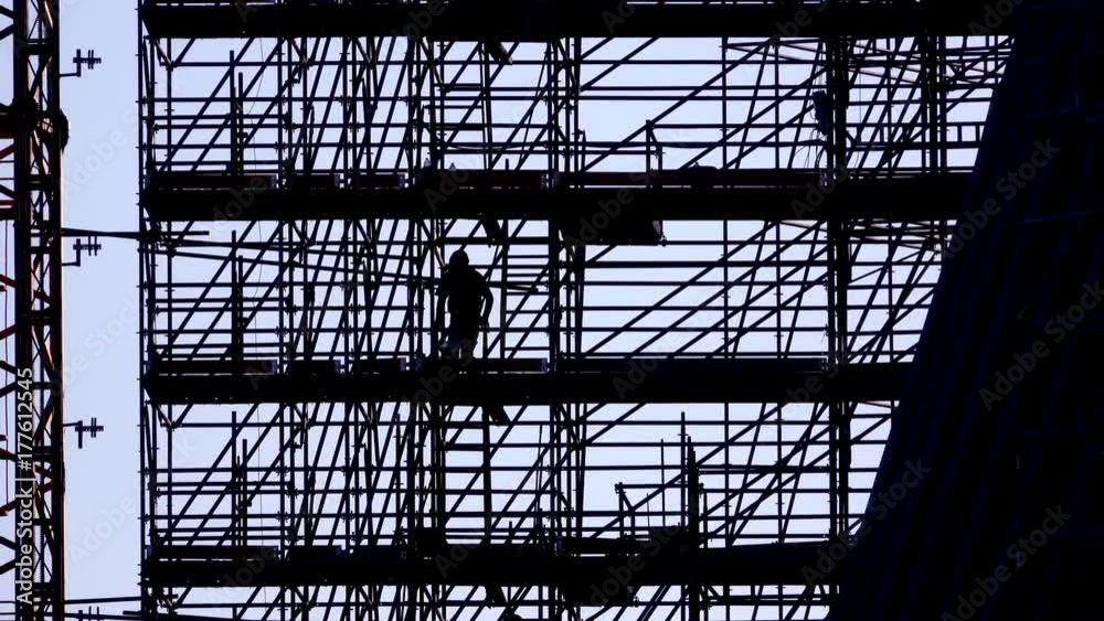 silhouette of workers going down scaffolding stairs, leaving work, ends the working day at building construction