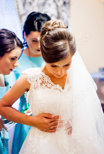 Sweet bride's girlfriends help dress their clothes