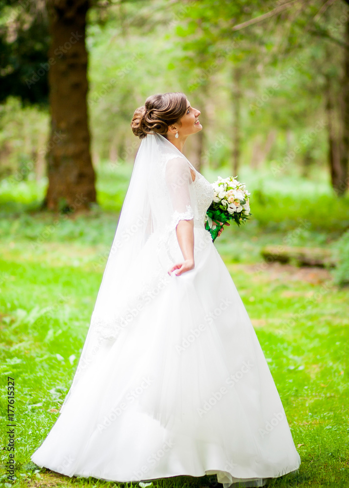 Dreamy young bride holds green bouquet