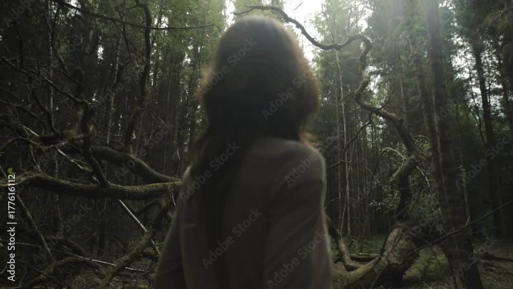 Young woman in the mistery woods standing by the fallen tree Young woman in the mistery woods standing by the fallen tree