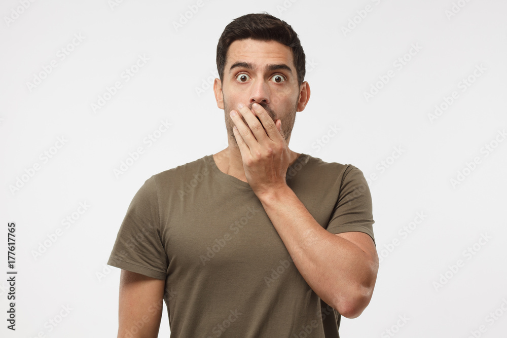 Astonished bug-eyed student covering his mouth with one hand, looking shocked. Surprised, embarrassed and confused young male showing omg emotion Astonished bug-eyed student covering his mouth with one hand, looking shocked. Surprised, embarrassed and confused young male showing omg emotion