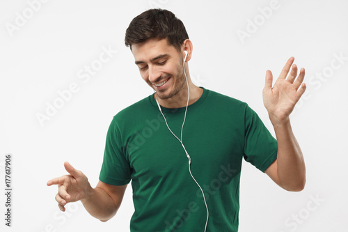 My favourite song. Young happy man smiling, listening music via headphones, dancing with closed eyes isolated on gray background.