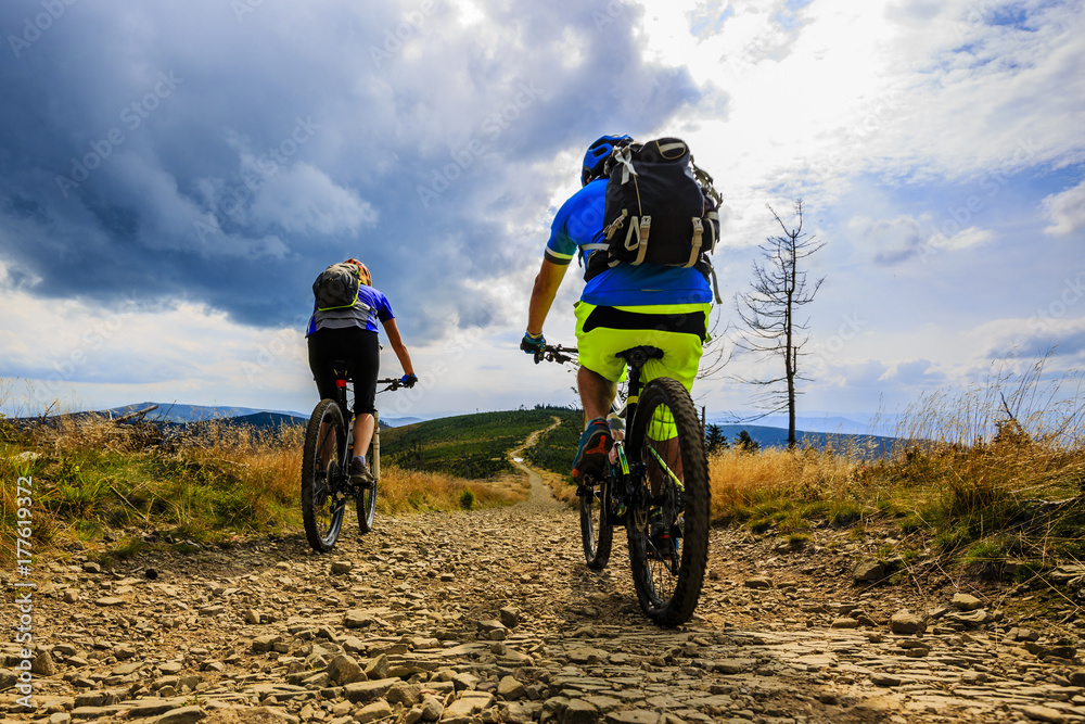 Fototapeta premium Cycling, mountain biker couple on cycle trail in autumn forest. Mountain biking in autumn landscape forest. Man and woman cycling MTB flow uphill trail.