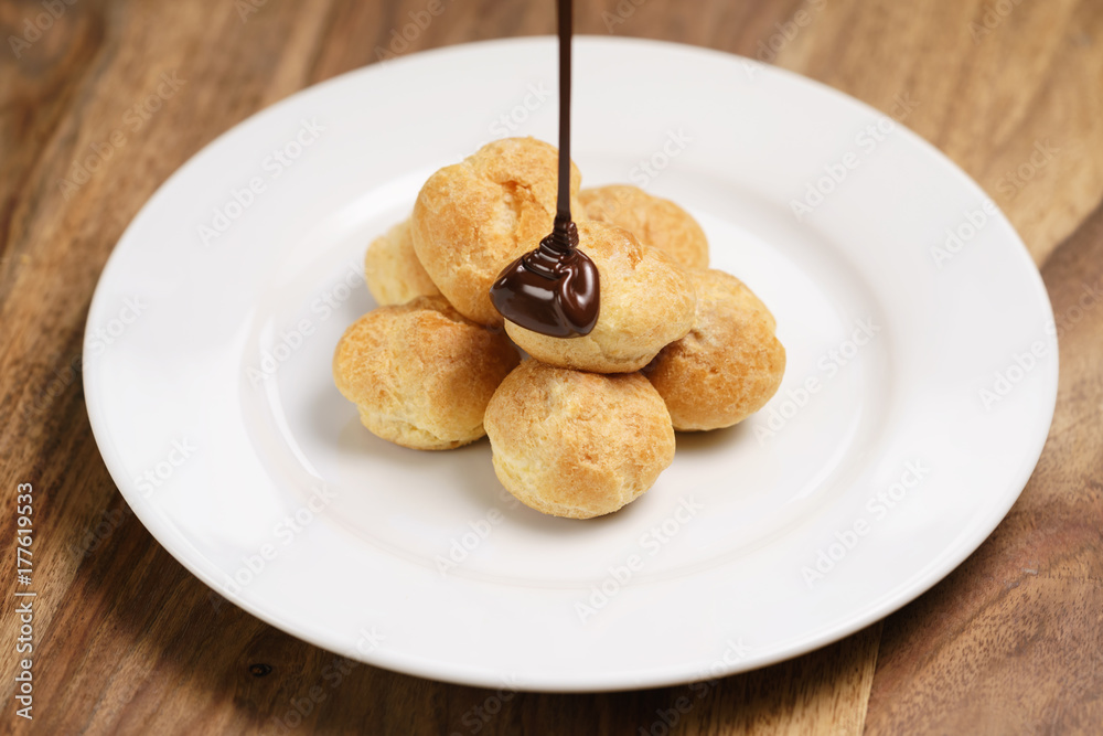 pour chocolate on profiteroles on plate closeup pour chocolate on profiteroles on plate closeup