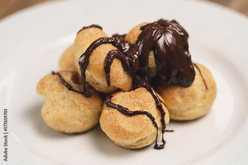 profiteroles covered with black chocolate on plate closeup profiteroles covered with black chocolate on plate closeup