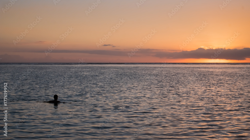 man swimming in the sunset