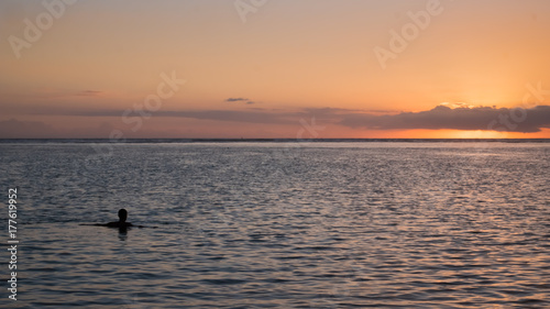 man swimming in the sunset