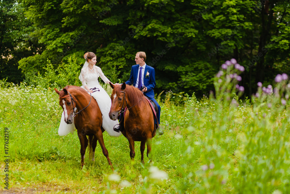 Beautiful newlyweds riding two horses Beautiful newlyweds riding two horses