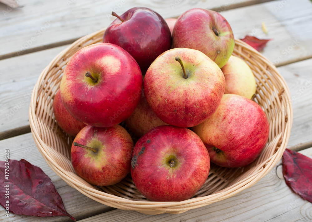Fresh red yellow apples in wicker plate on wooden table. Concept for seasonal fruits, autumn harvest and agriculture. Fresh red yellow apples in wicker plate on wooden table. Concept for seasonal fruits, autumn harvest and agriculture.