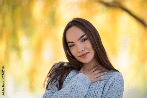 Portrait of brunette model with red lips smiling and posing in park on yellow background in autumn face close up, young fresh white pale skin