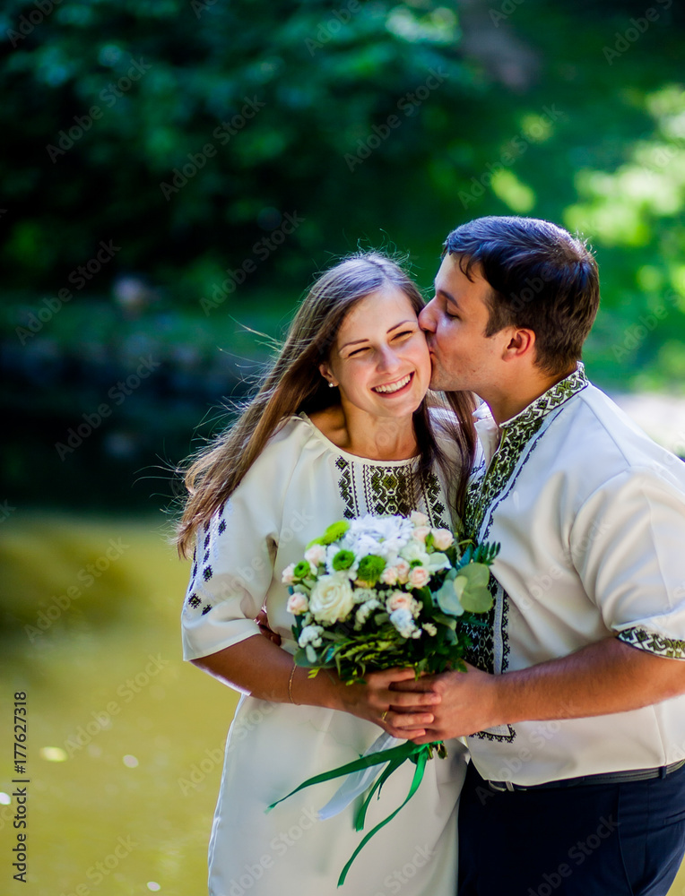 Amazing couple is standing in the park holding a bunch of flowers Amazing couple is standing in the park holding a bunch of flowers
