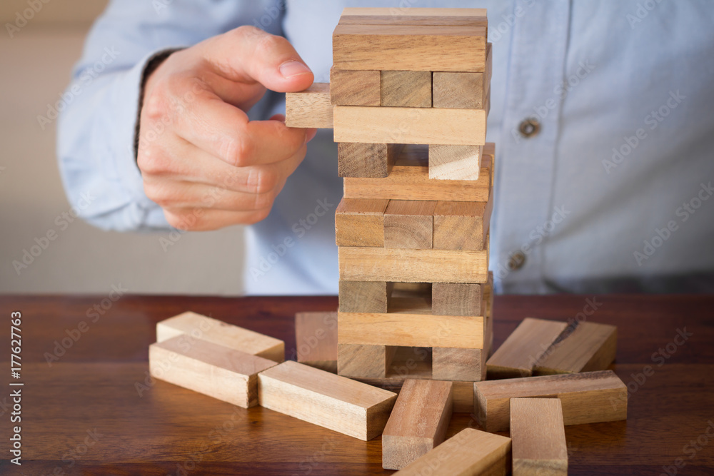 hand of businessman pulling out or placing wood block on tower hand of businessman pulling out or placing wood block on tower
