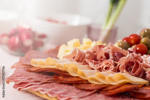 Tray with bacon, cheese cubes, salami, ham; with spring onions in the background