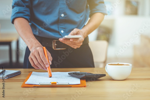 Business man working document in coffee shop morning light.