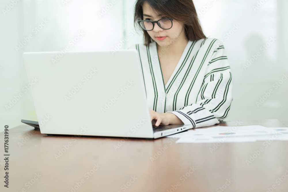 Young business woman working on laptop in office. Young business woman working on laptop in office.