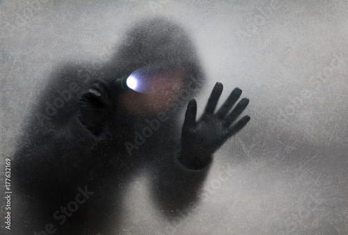Thief with flashlight behind a dusty scratched glass photo