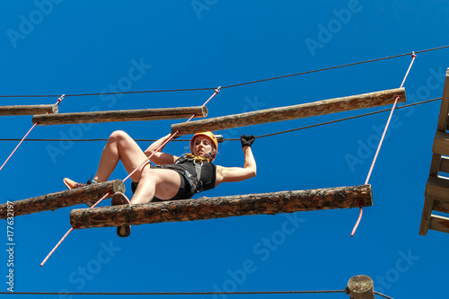 Adventure climbing rope park - a young woman in protective gear passes the track on a rope simulator. training mountaineers in the mountains. leisure in nature. sports streets