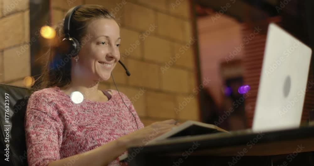woman using laptop and headset communicating while sitting in cafe woman using laptop and headset communicating while sitting in cafe