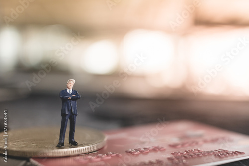 Miniature people businessman standing on coin