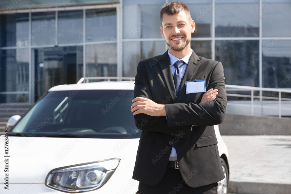 Salesman standing near new car outdoors