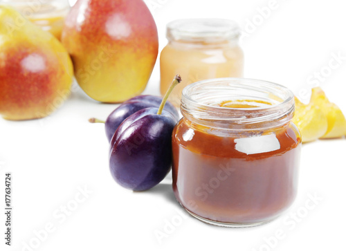 Jar with tasty baby food and fresh plums on white background