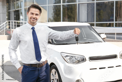 Salesman with key standing near new car outdoors © Africa Studio