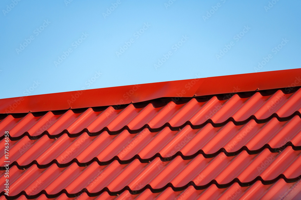 Fragment of red a metal tile roof a background of blue sky Fragment of red a metal tile roof a background of blue sky