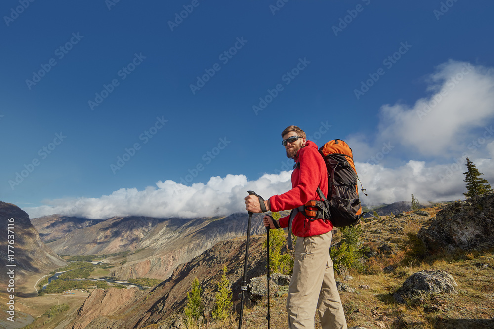Handsome young male hiker sitting on the edge of a canyon looking away